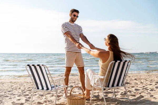 Happy couple sitting in folding chairs on beach — Stock Photo, Image