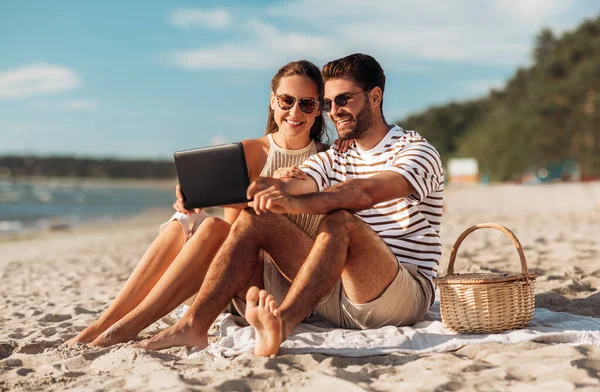 Couple heureux avec tablette pc au pique-nique sur la plage — Photo