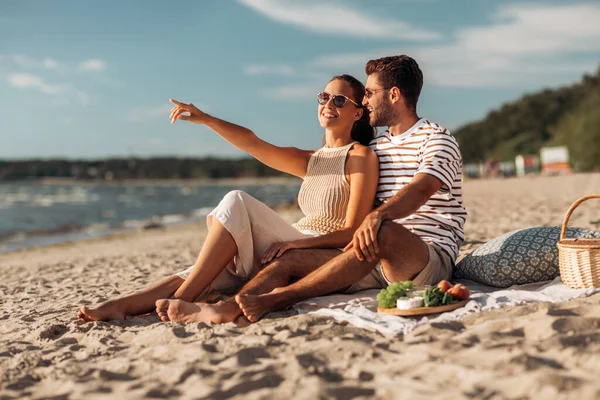 Casal feliz com comida fazendo piquenique na praia — Fotografia de Stock