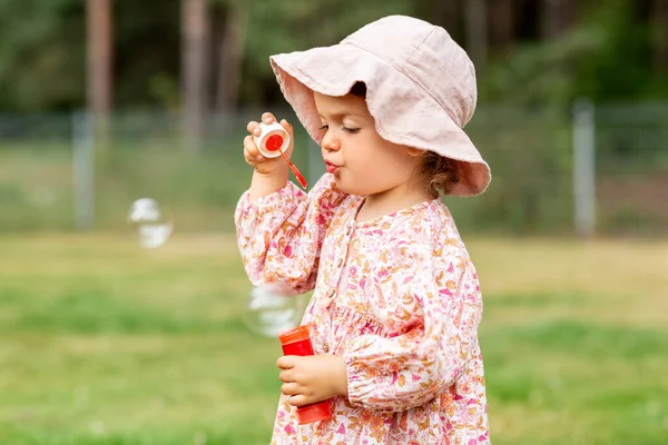 Happy baby girl blowing soap bubbles in summer — Stock Photo, Image