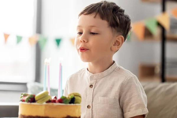 Šťastný malý chlapec foukání svíčky na narozeninový dort — Stock fotografie