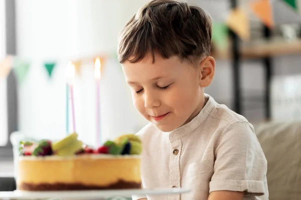 Menino feliz soprando velas no bolo de aniversário — Fotografia de Stock