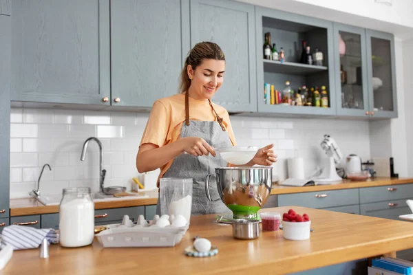Щаслива молода жінка готує їжу на кухні вдома — стокове фото