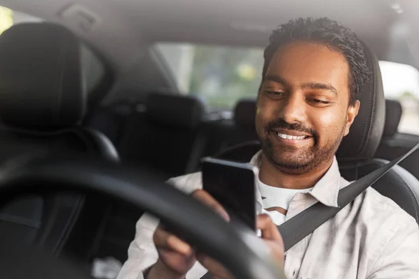 Hombre indio sonriente en el coche usando teléfono inteligente —  Fotos de Stock