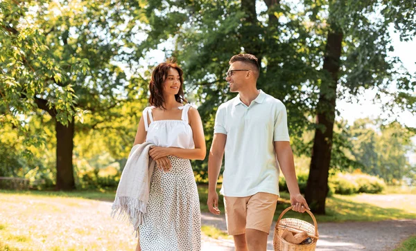 Pareja feliz con cesta de picnic en el parque de verano —  Fotos de Stock