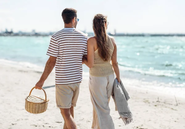 Ευτυχισμένο ζευγάρι με καλάθι πικ-νικ περπάτημα στην παραλία — Φωτογραφία Αρχείου