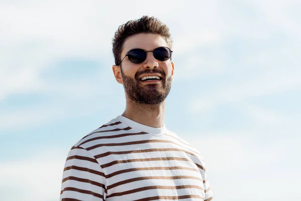 Усміхнений молодий чоловік в сонцезахисних окулярах над небом — стокове фото