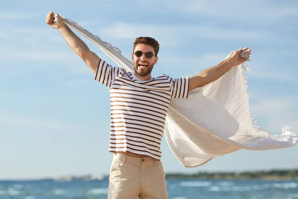 Lächelnder Mann mit Sonnenbrille und Decke am Strand — Stockfoto