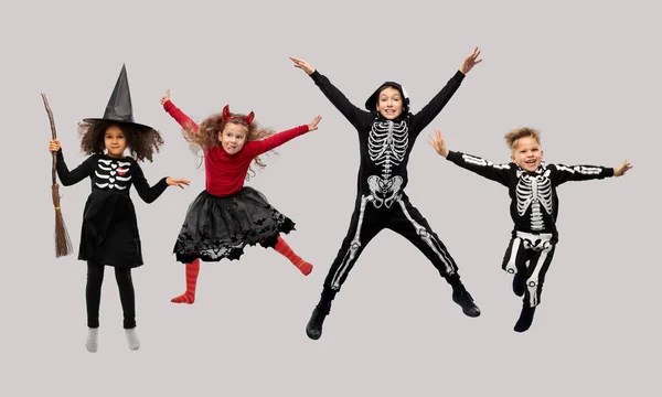 Niños felices en disfraces de Halloween saltando —  Fotos de Stock