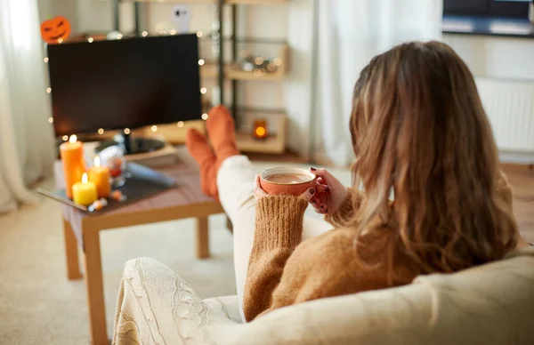 Vrouw kijkt tv en drinkt cacao op halloween — Stockfoto