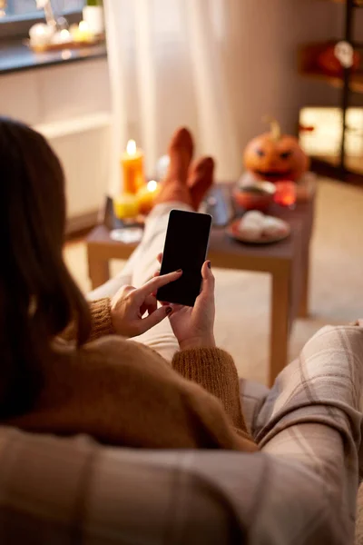 Woman using smartphone at home on halloween — Stock Photo, Image