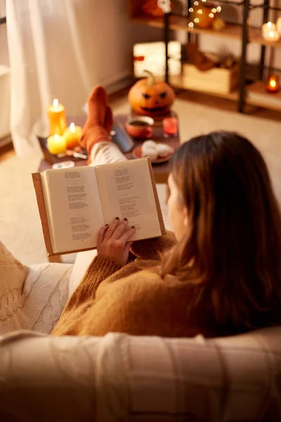 Junge Frau liest an Halloween zu Hause Buch — Stockfoto