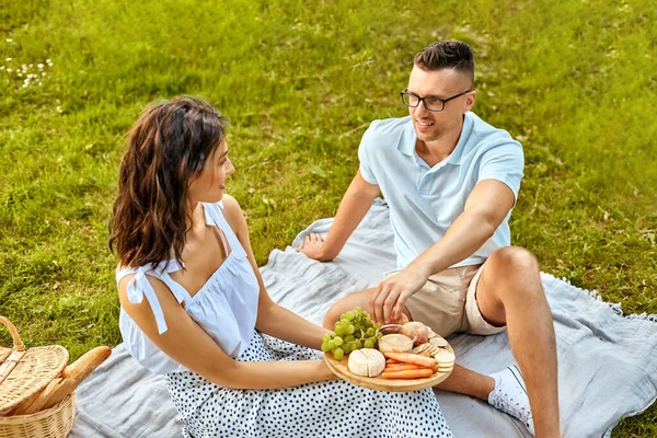 Счастливая пара устраивает пикник в летнем парке — стоковое фото
