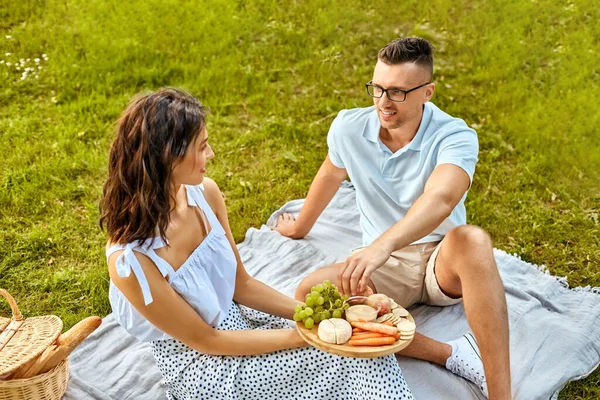 Casal feliz fazendo piquenique no parque de verão — Fotografia de Stock