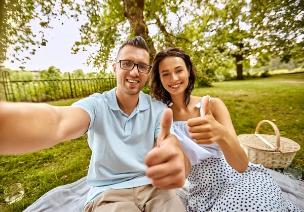 Pareja tomando selfie y mostrando pulgares hacia arriba en el parque — Foto de Stock