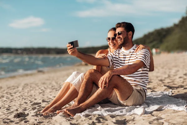 快乐的夫妻在海滩上用智能手机自拍 — 图库照片
