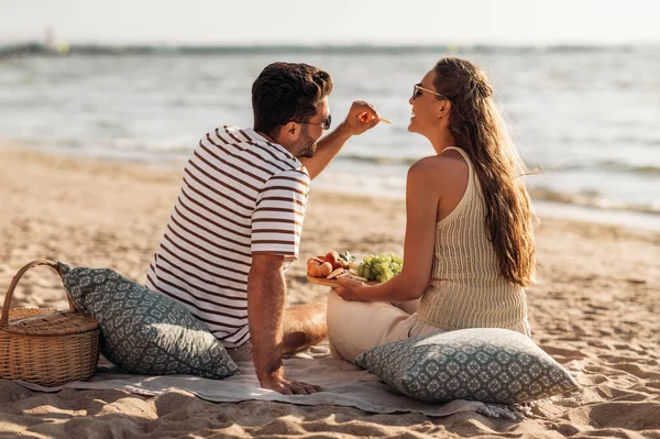 Felice coppia con cibo avendo pic-nic sulla spiaggia — Foto Stock