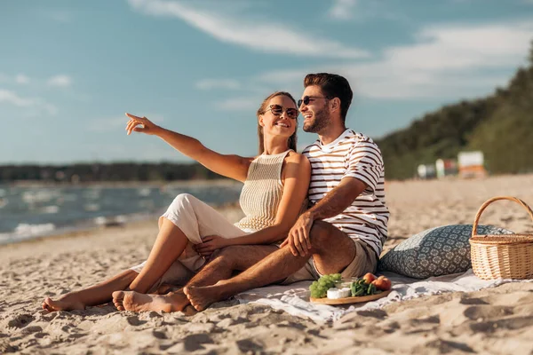 Šťastný pár s jídlem piknik na pláži — Stock fotografie