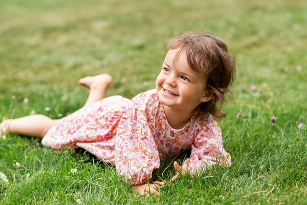 Menina pequeno feliz deitado na grama no verão — Fotografia de Stock