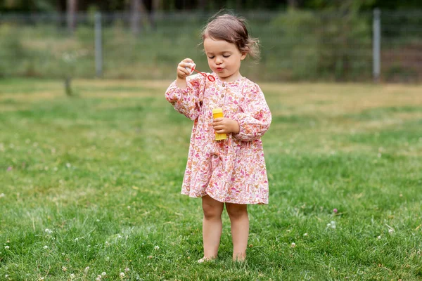Heureux bébé fille soufflant bulles de savon en été — Photo