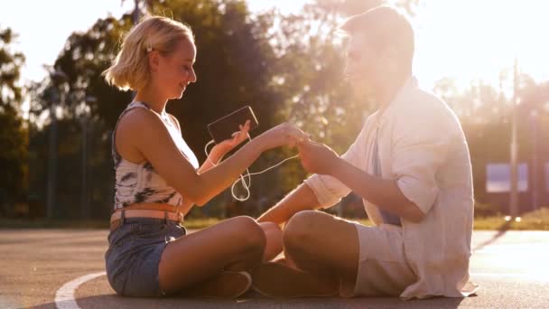 Happy couple with smartphone and earphones in city — Stock Video