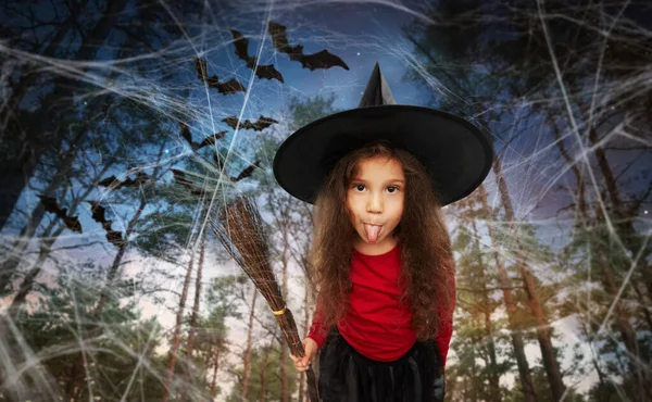검은 마녀 모자를 쓰고 할로윈에 빗자루를 들고 있는 소녀 — 스톡 사진