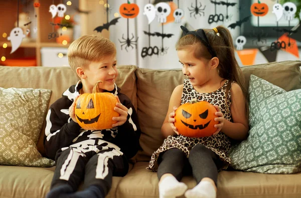 Ungar i halloween kostymer med pumpor hemma — Stockfoto