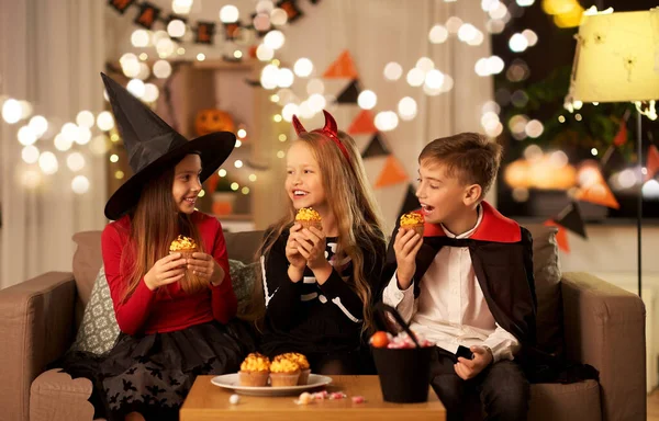 ハロウィンの衣装を着た子供たちが家でカップケーキを食べて — ストック写真