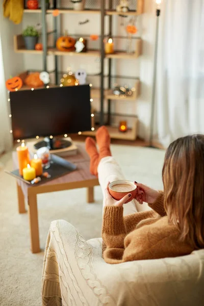 Nő néz tv-t és iszik kakaót halloween — Stock Fotó