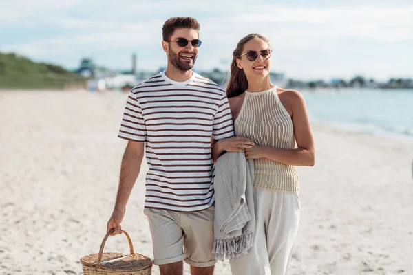 Coppia felice con cestino da picnic passeggiando sulla spiaggia — Foto Stock