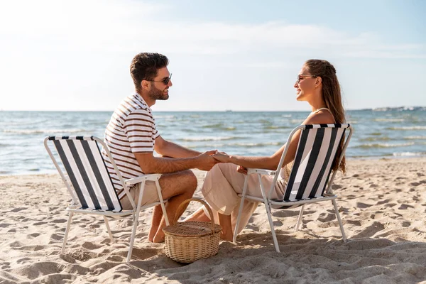 Heureux couple assis dans des chaises pliantes sur la plage — Photo