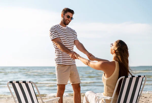 Feliz casal sentado em cadeiras dobráveis na praia — Fotografia de Stock