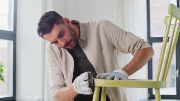 Hombre con esponja lijar silla de madera vieja en casa — Vídeo de stock