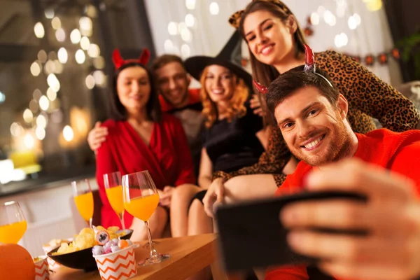 Amigos felices en disfraces de Halloween tomando selfie —  Fotos de Stock