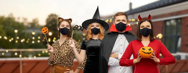 Amigos en disfraces de Halloween y máscaras negras — Foto de Stock