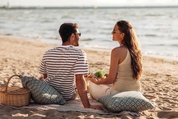 Glückliches Paar mit Essen beim Picknick am Strand — Stockfoto