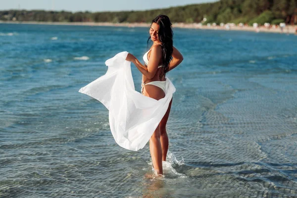 비키니를 입은 여자 가 해변에서 이불을 덮고 수영을 한다 — 스톡 사진