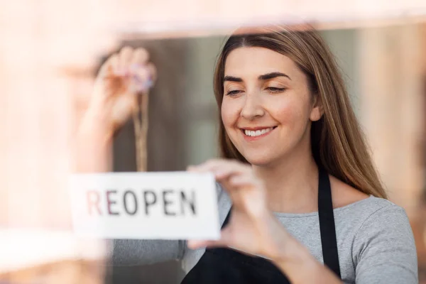 Femme heureuse accrochant bannière rouverte au verre de porte — Photo