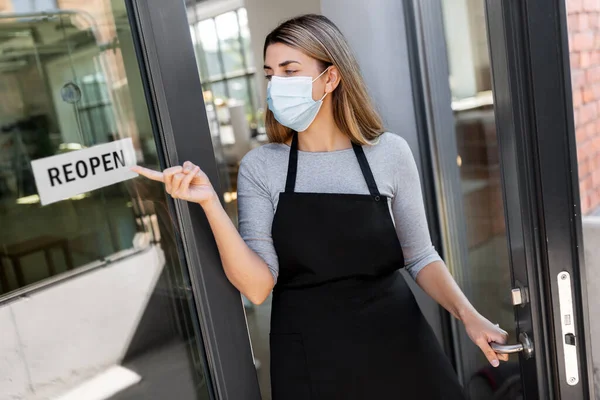 Woman in mask showing reopen banner on door glass — Stock Photo, Image