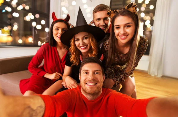 Amigos felices en disfraces de Halloween tomando selfie —  Fotos de Stock