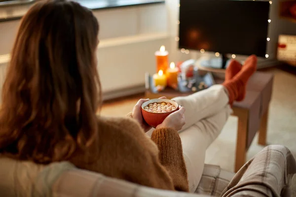 女性はテレビを見てハロウィンにココアを飲む — ストック写真