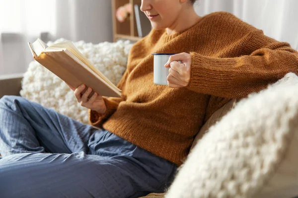 Vrouw die thuis koffie drinkt en boek leest — Stockfoto