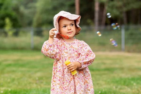 Glad liten flicka blåser såpbubblor på sommaren — Stockfoto