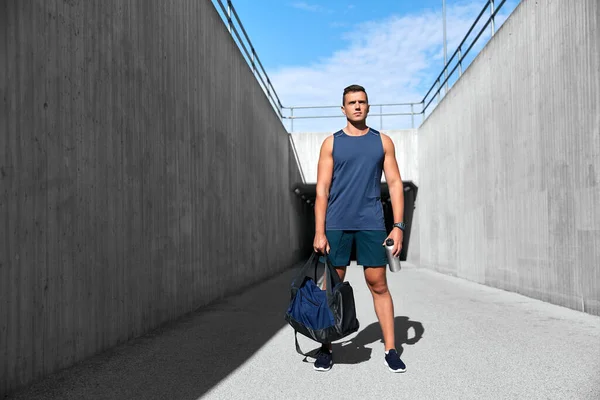 Sportsman with bag and bottle walking outdoors — Stock Photo, Image