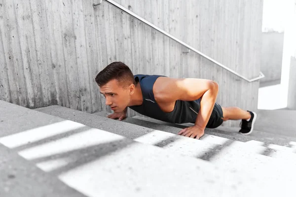 Young man doing push ups on stairs outdoors — Stock Photo, Image