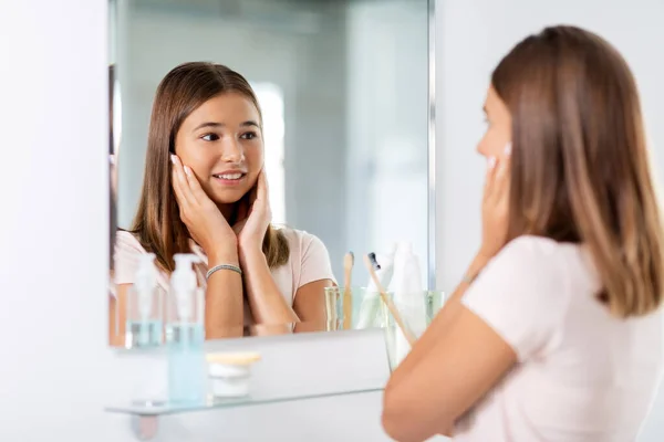 Teenagermädchen schaut im Spiegel auf Badezimmer — Stockfoto