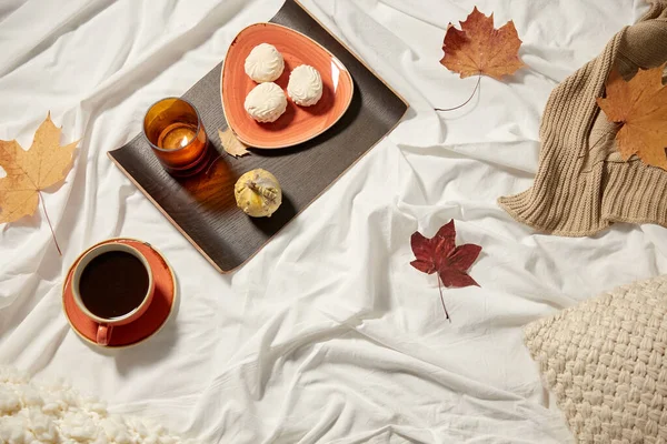 Xícara de café, folhas de outono e vela na cama — Fotografia de Stock