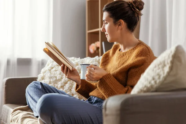 Evde kahve içip kitap okuyan bir kadın. — Stok fotoğraf