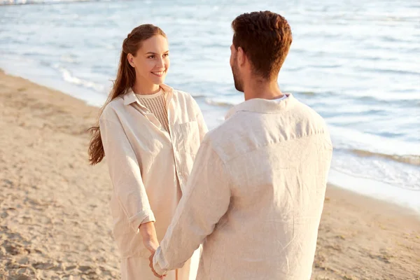 Счастливая пара, держащаяся за руки на летнем пляже — стоковое фото
