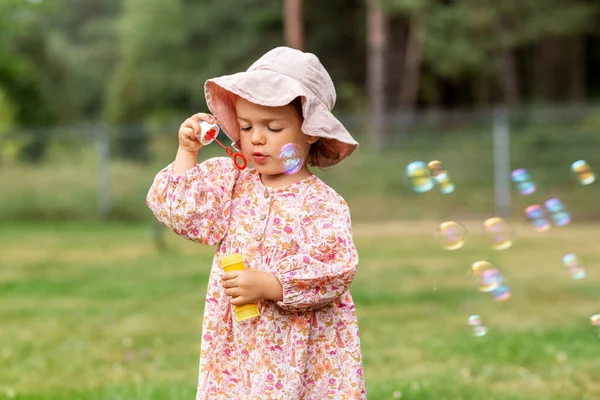 Happy baby girl blowing soap bubbles in summer — Stock Photo, Image